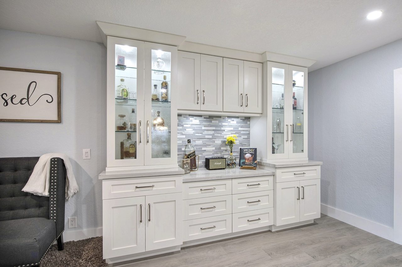 Built-in bar cabinetry with glass-front uppers over wood-look plank flooring