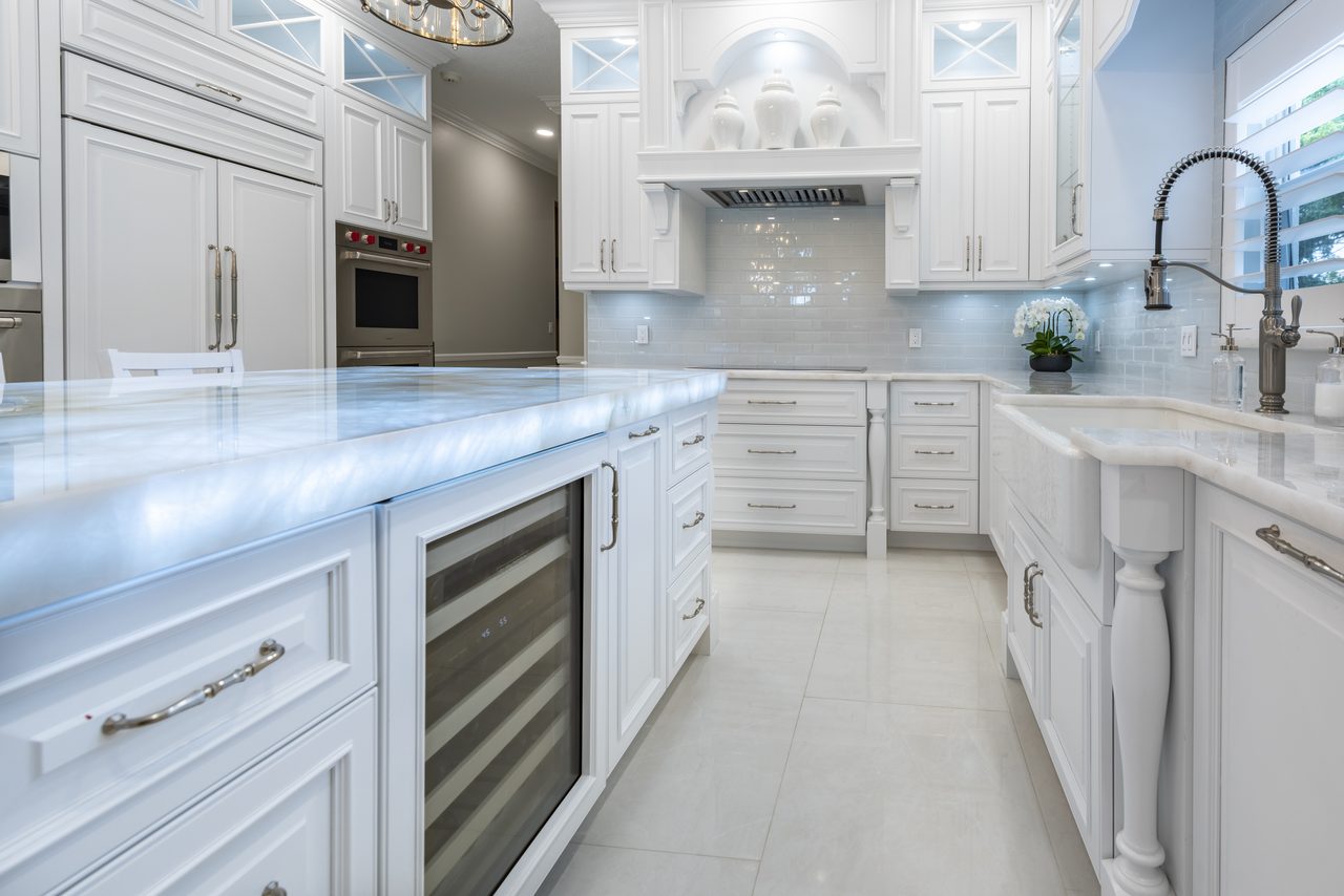Cabinetry built around integrated wine refrigeration and a farmhouse sink