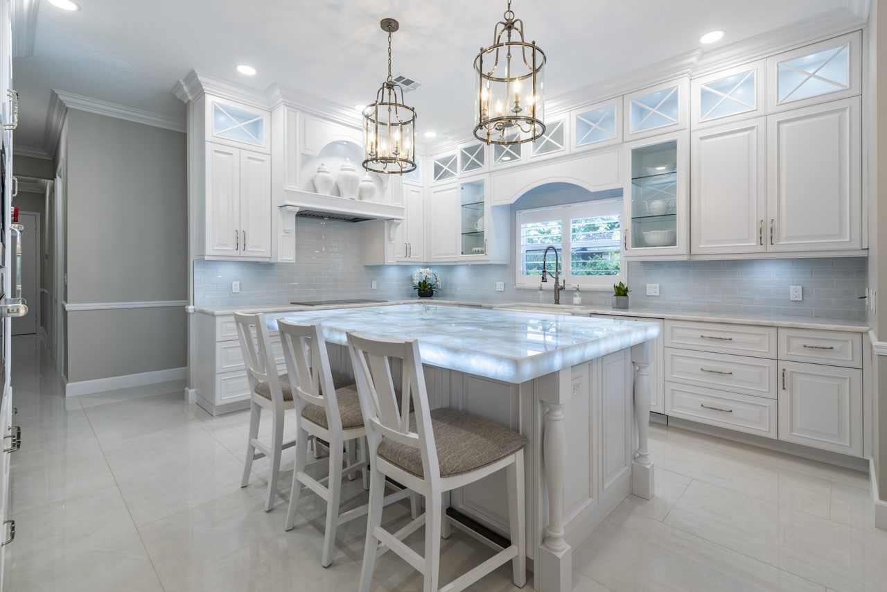 Classic white kitchen with a backlit stone island and glass-front upper cabinets
