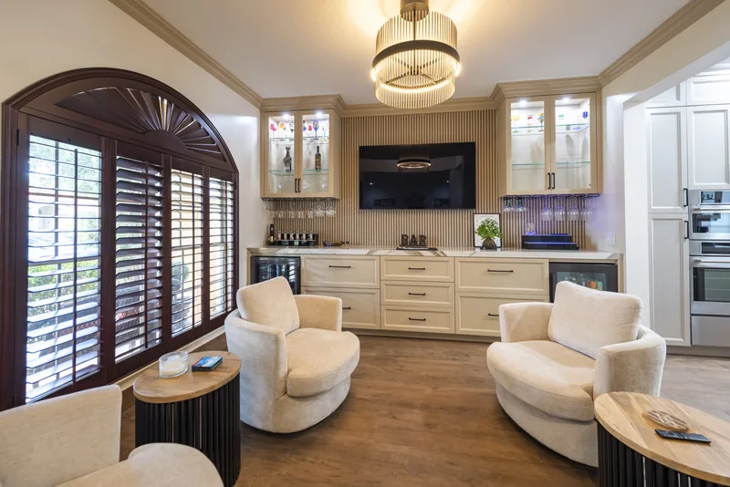 Custom fluted wood paneling and glass-front cabinetry built around a home bar