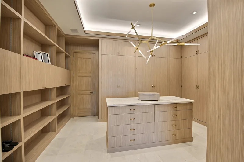 Custom oak walk-in closet with a marble-top island and brass hardware