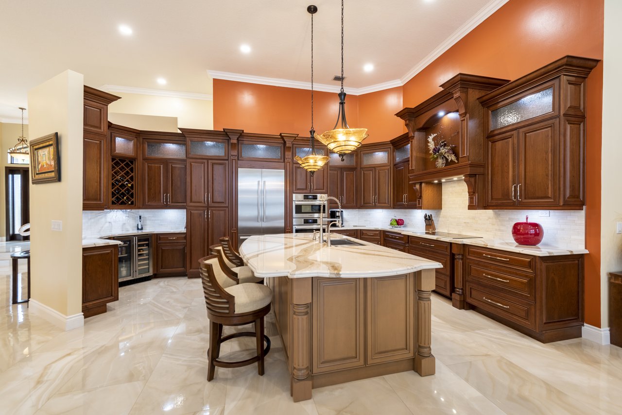 Traditional cherry-toned kitchen with a curved island, raised-panel cabinetry, and a built-in wine rack