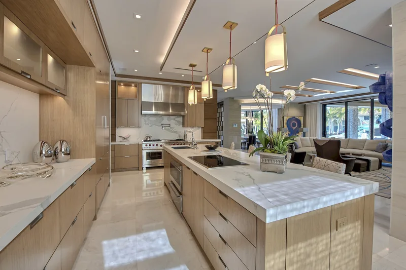 Open modern kitchen with rift-cut oak cabinetry and a marble waterfall island