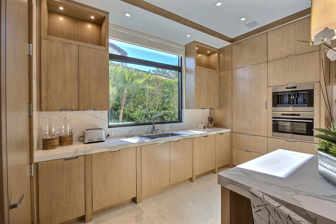 Modern kitchen with rift-cut oak cabinetry, integrated Wolf coffee system and double wall oven, and a marble waterfall island