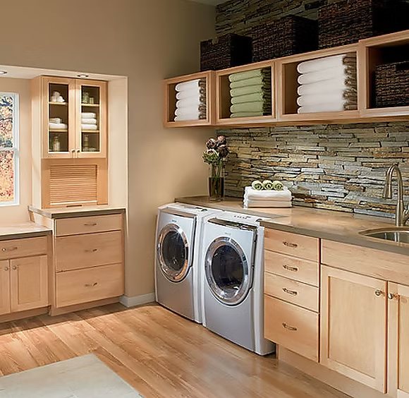 Laundry room with washer and dryer set into custom maple cabinetry with open shelving