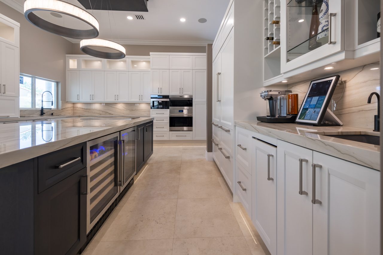 Modern galley with integrated wine refrigeration, stone countertops and built-in ovens beyond