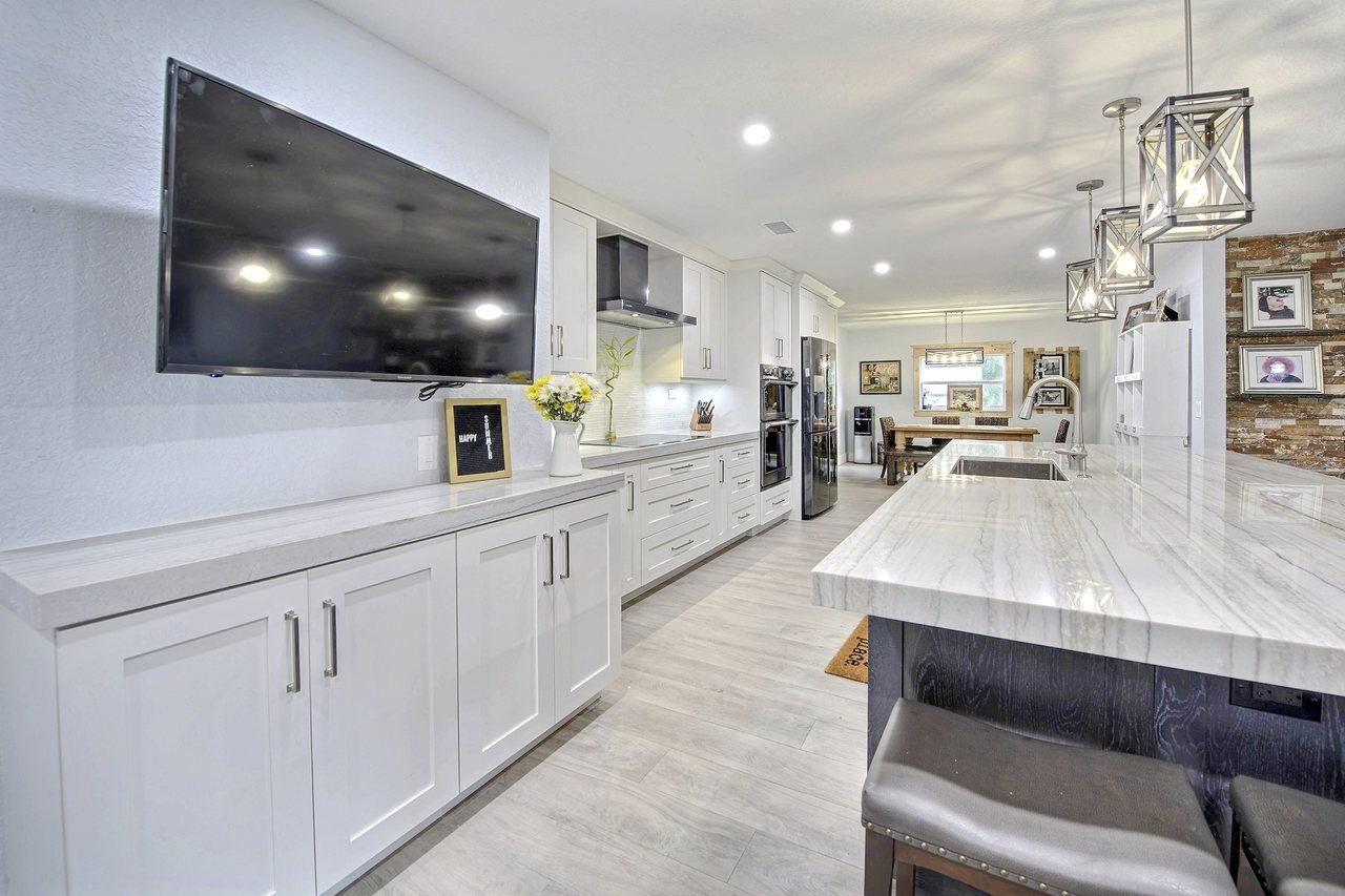 Wood-look plank flooring running the length of an open white kitchen and dining space